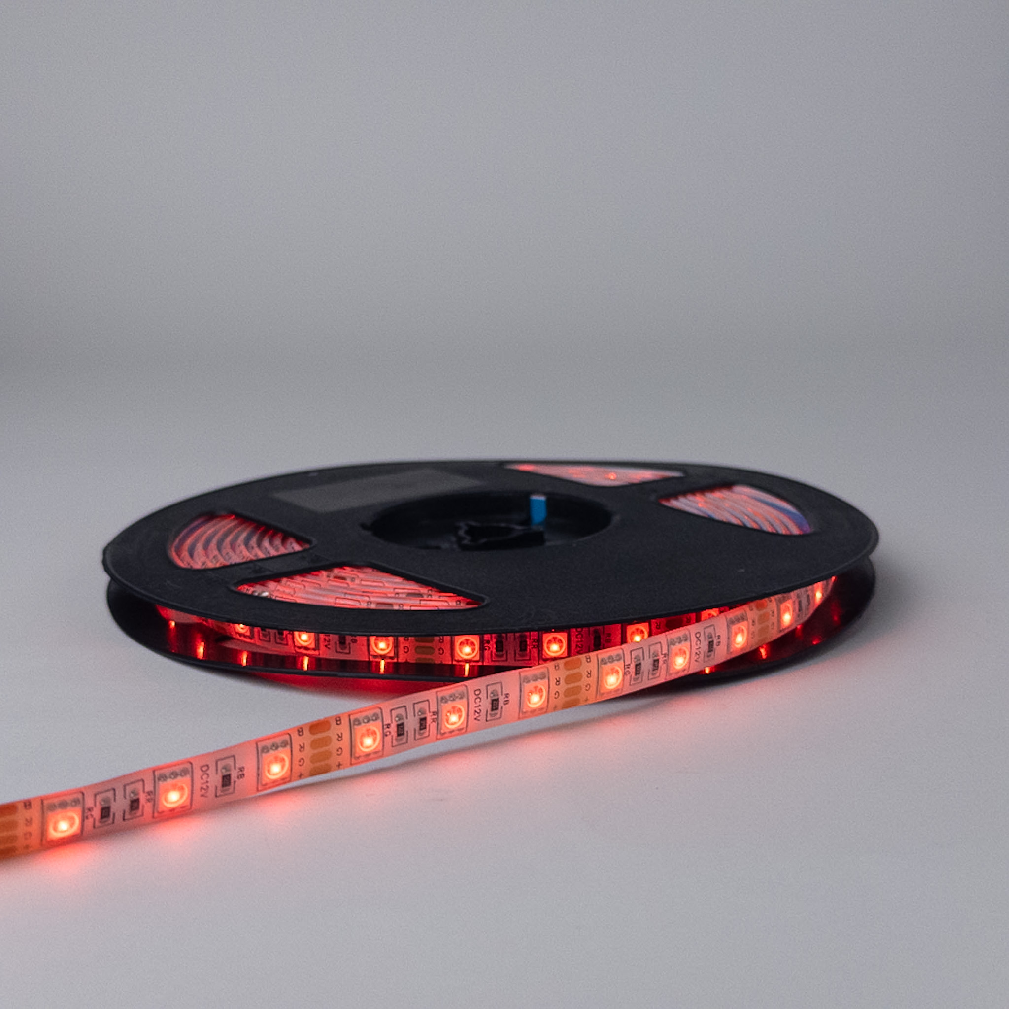 Traka sa 60 RGB dioda po metru upaljena u crvenoj boji, sa crvenim odsjajem na koturu i podlozi
